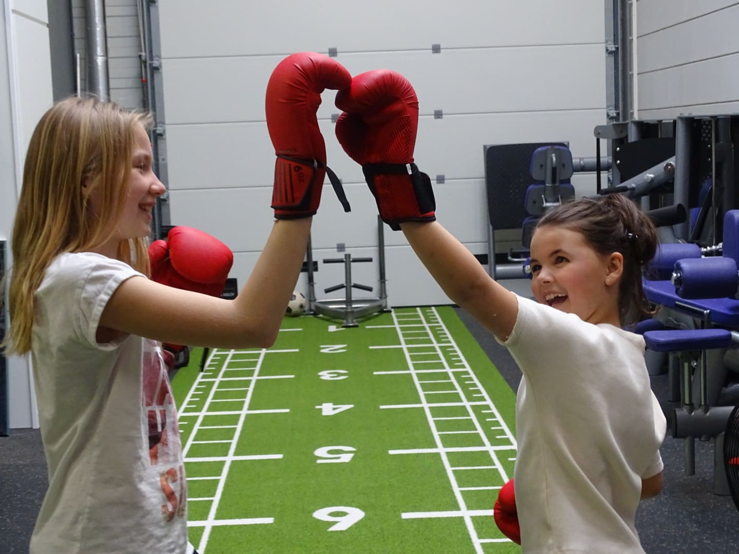 Twee kinderen met rode bokshandschoenen geven elkaar een high five