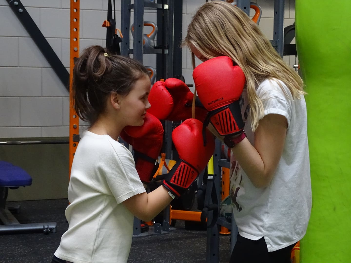 Twee kinderen oefenen een stoot met rode bokshandschoenen
